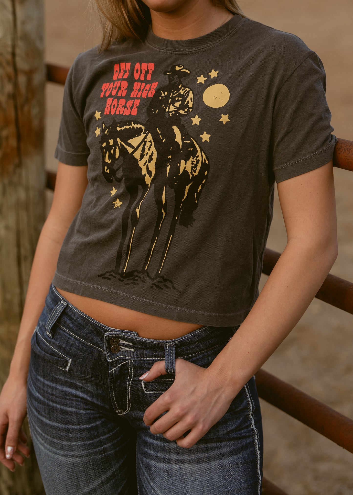 Person wearing a graphic t-shirt with a horse and text design outdoors.