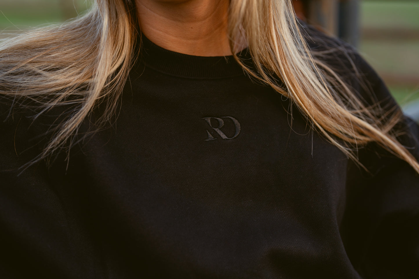closeup of girl wearing cropped black western warmup hoodie Ranch Dress'n embroidered tone on tone RD