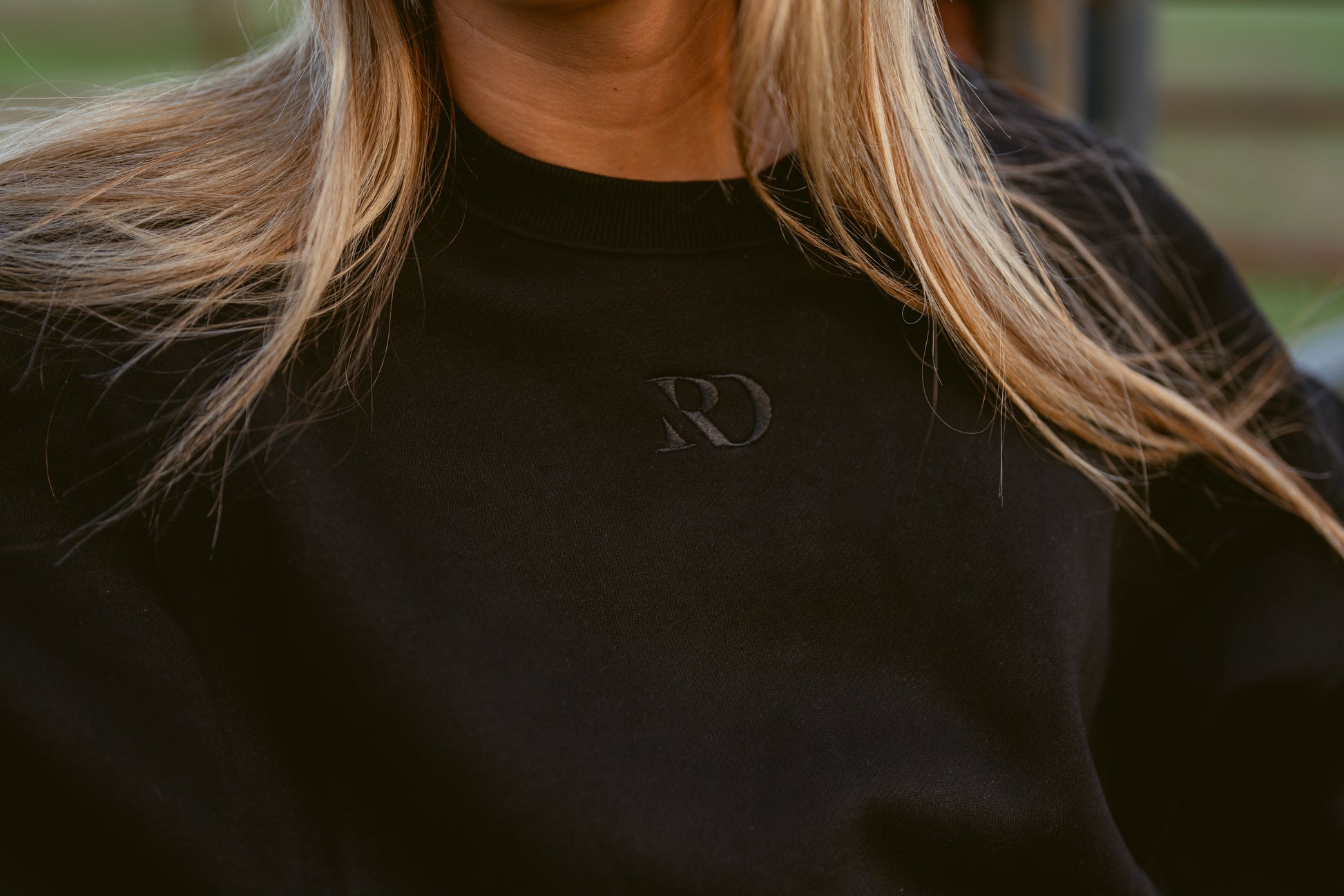 closeup of girl wearing cropped black western warmup hoodie Ranch Dress'n embroidered tone on tone RD