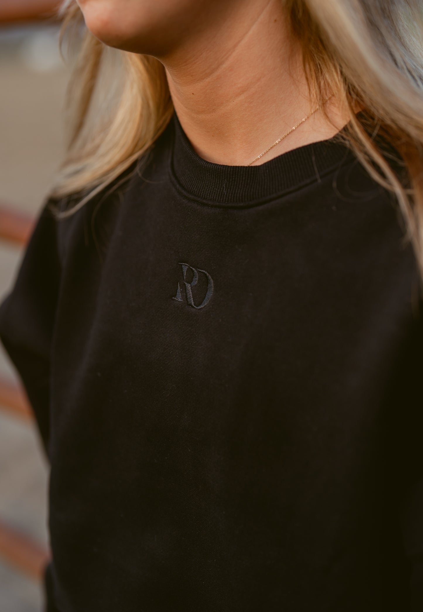closeup of girl wearing cropped black western warmup hoodie Ranch Dress'n embroidered tone on tone RD